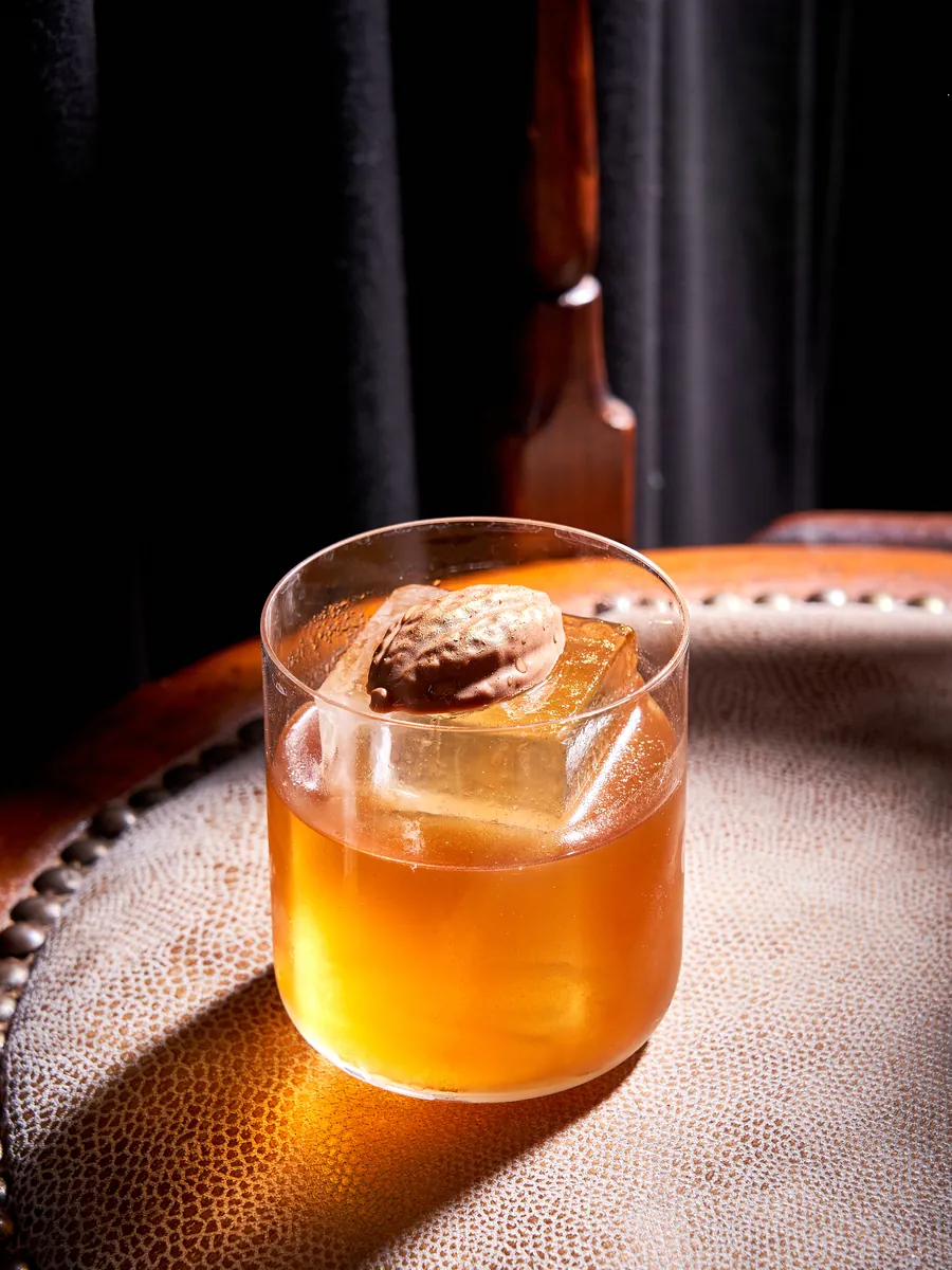 Cocktail Inima Nucatei — lichior de nucă și Campari, cu cub mare de gheață și nucă, COVOR BAR Chișinău